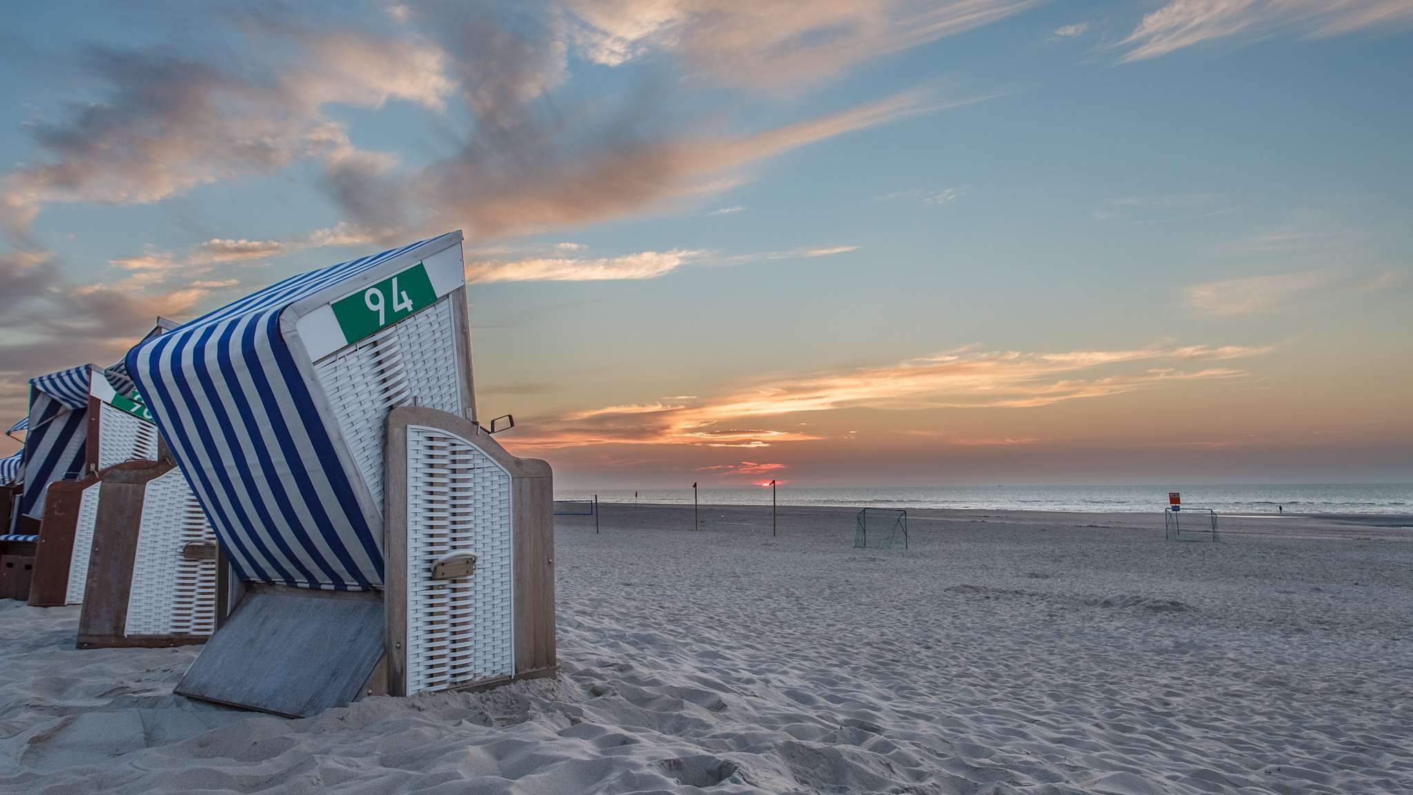 Strandkörbe an einem Strand bei Sonnenuntergang